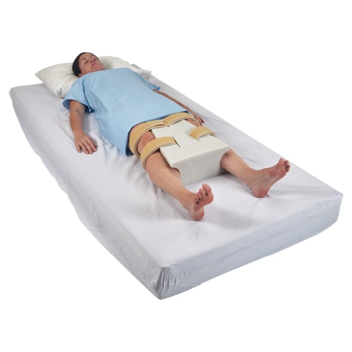 Close-up of a white foam abduction pillow with velcro straps on a hospital bed
