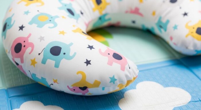 Close-up of a crescent-shaped tummy time pillow with removable washable cover on a play mat