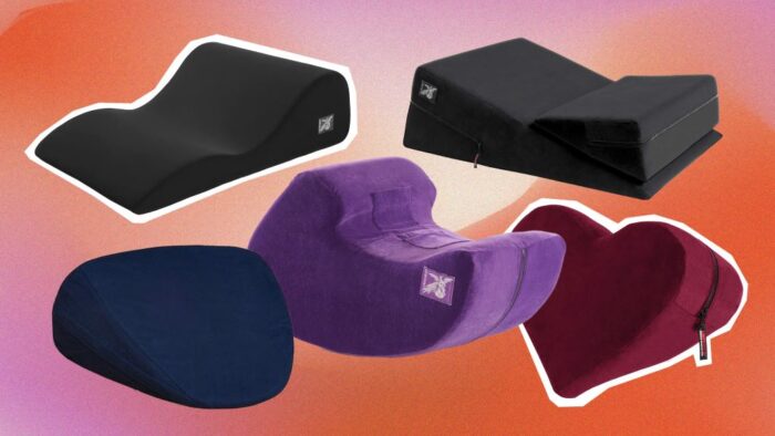 A collection of various ergonomic intimacy pillows, including wedges and ramps, displayed on a bed to show different support shapes.
