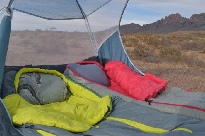 Camper using a compressible camping pillow inside a tent for better sleep